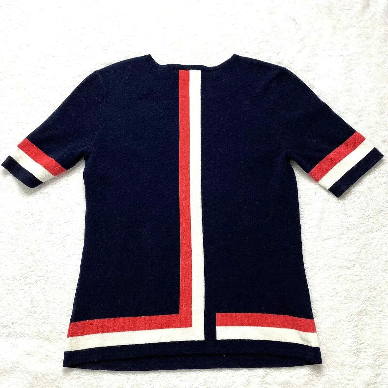 Cabi Hampton Shell Knit Top, is Navy with red and White Stripe at Sleeve and Hem.
